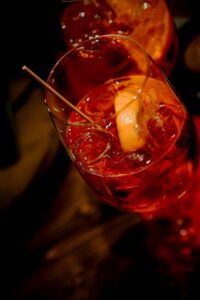 A vibrant Aperol spritz cocktail in a glass with an orange slice, photographed in a Venice bar.