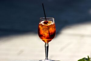 Close-up of a chilled Aperol Spritz with orange slice in sunny outdoor setting.