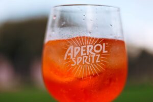 Refreshing Aperol Spritz cocktail on a sunny day with a blurred outdoor background.