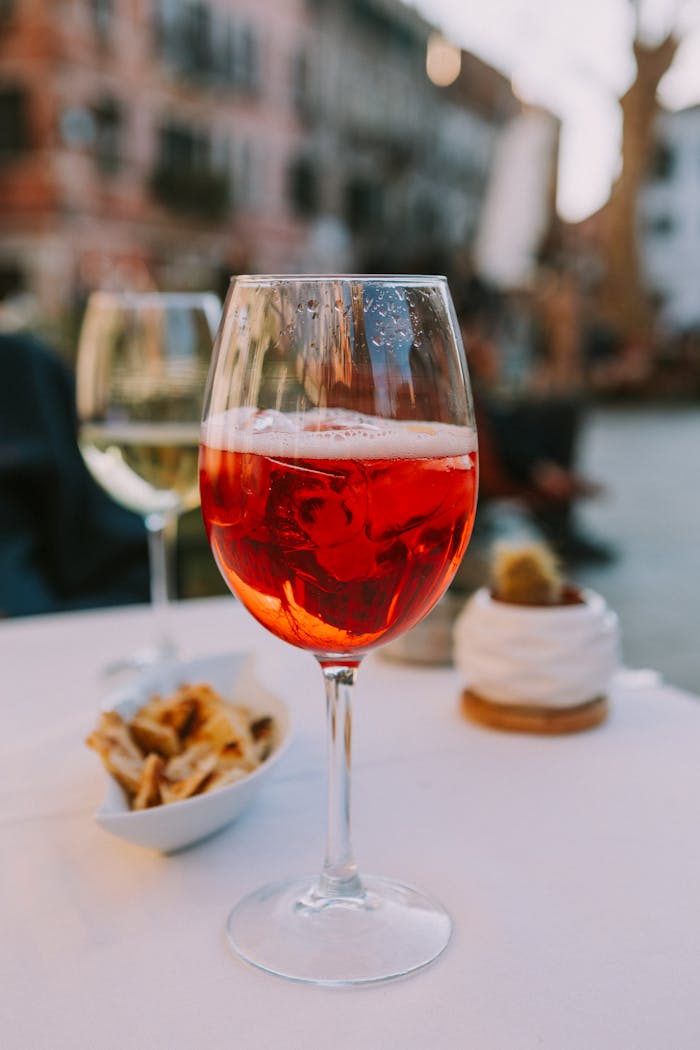 Aperol Spritz on a table in an outdoor setting with appetizers and warm ambiance.